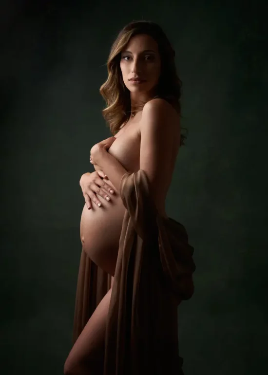 photo de grossesse avec une femme portant un voile dorée sur un fond vert peint à la main en studio