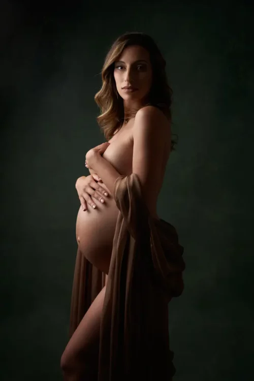 photo de grossesse avec une femme portant un voile dorée sur un fond vert peint à la main en studio