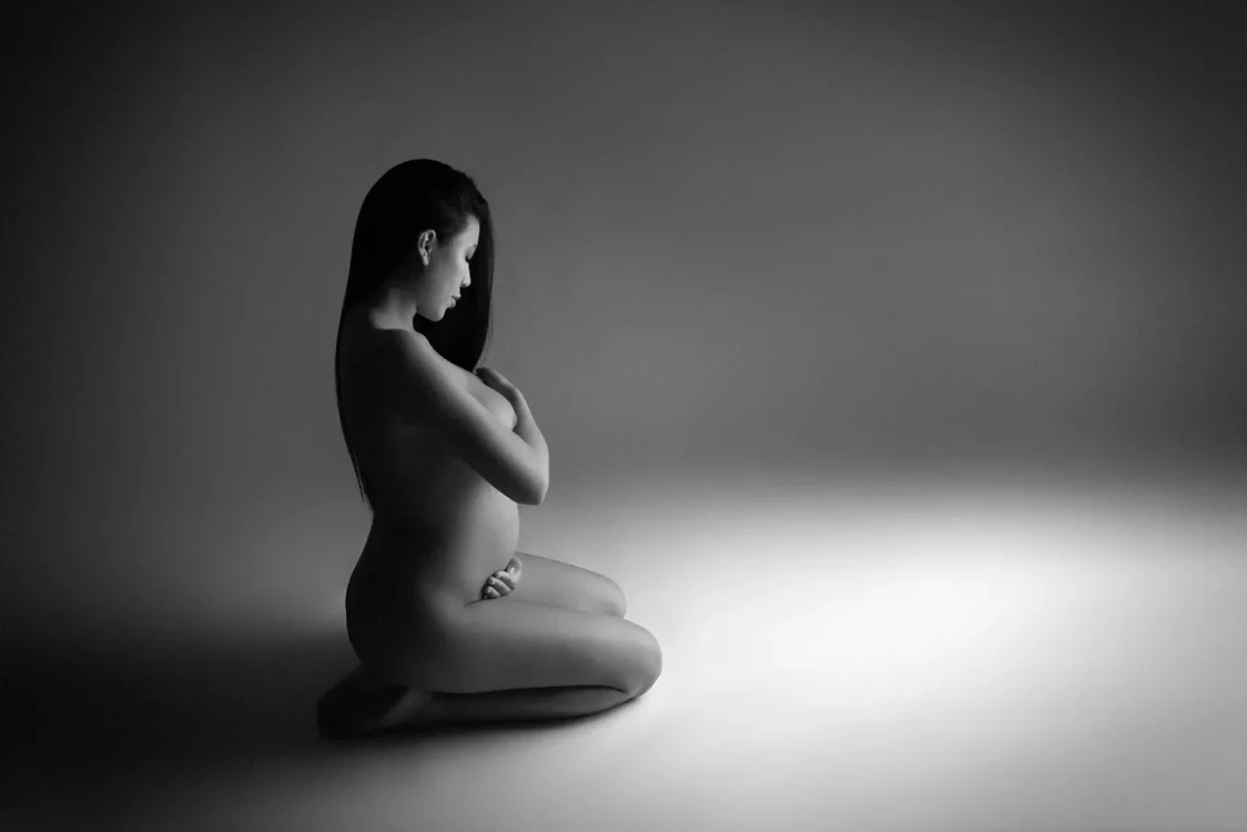 Photo de grossesse d'une femme nue artistique sur un fond gris en studio