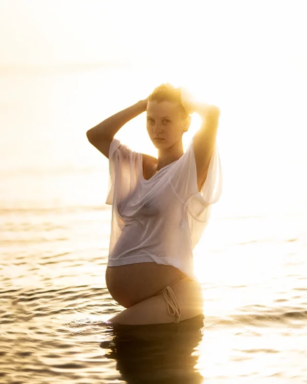 Femme enceinte posant dans l'eau au coucher du soleil lors d'une séance photo grossesse haut de gamme près d'Aix-en-Provence